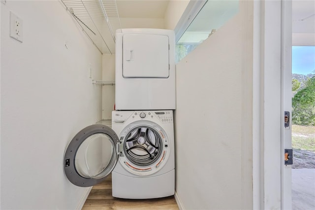 washroom featuring laundry area, light wood finished floors, and stacked washer / drying machine