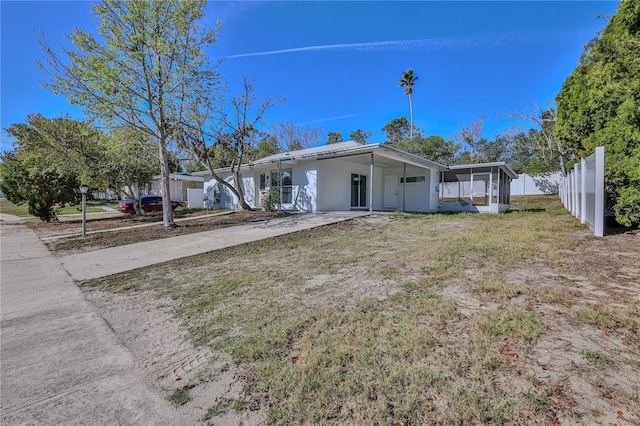 view of front of property featuring driveway, a sunroom, fence, and a front lawn