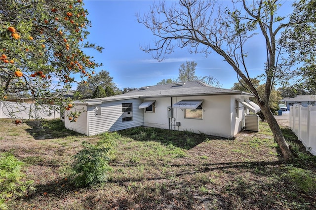 back of house with a lawn, fence, and stucco siding