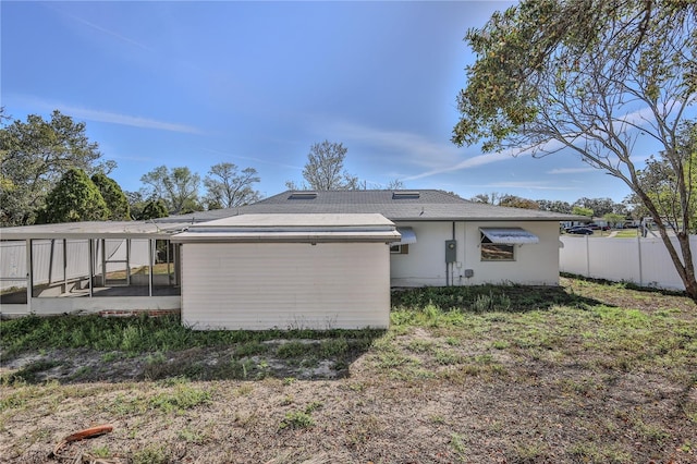 back of house featuring a carport, a sunroom, and fence