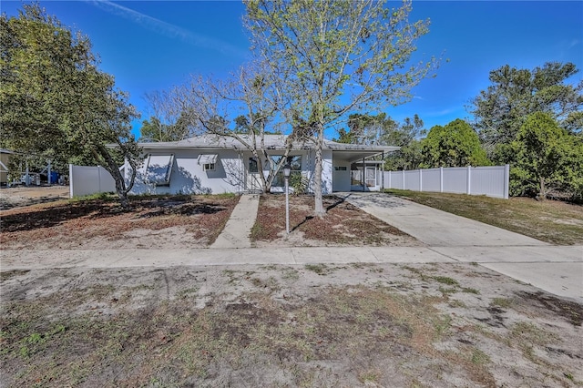 ranch-style home featuring an attached carport, driveway, and fence