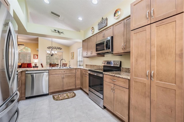 kitchen featuring lofted ceiling, a textured ceiling, a sink, visible vents, and appliances with stainless steel finishes