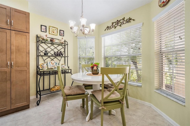 dining area featuring light tile patterned floors, baseboards, and a notable chandelier