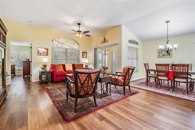 dining space featuring a textured ceiling, ceiling fan with notable chandelier, and wood finished floors