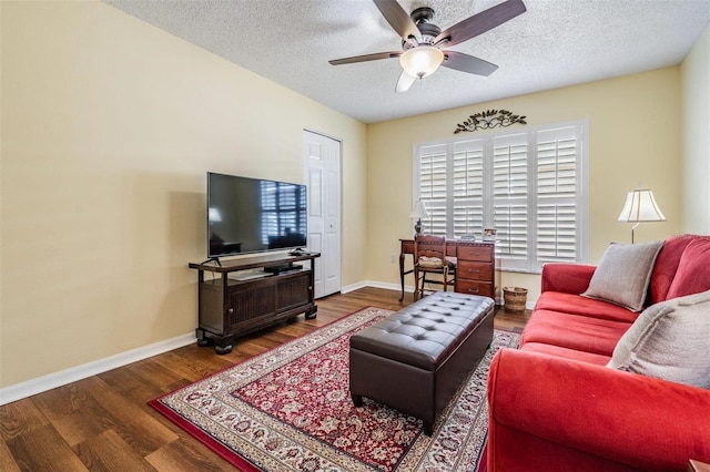 living area featuring ceiling fan, a textured ceiling, baseboards, and wood finished floors