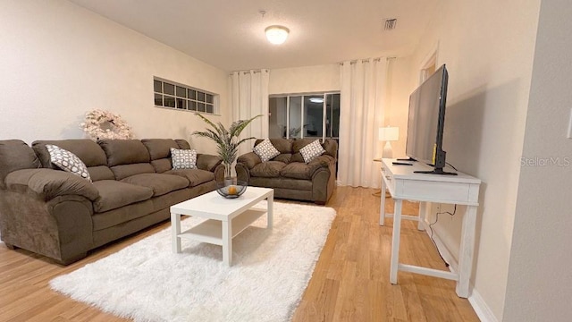 living area featuring light wood-type flooring, visible vents, and baseboards