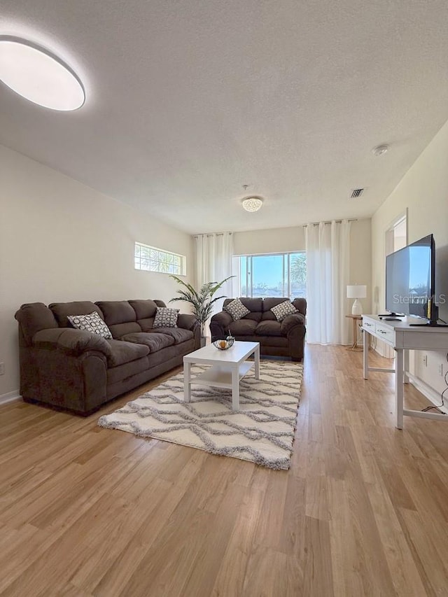 living room featuring a textured ceiling, visible vents, and wood finished floors