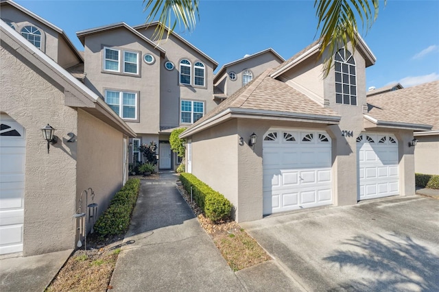 view of front of property with a garage, concrete driveway, a shingled roof, and stucco siding