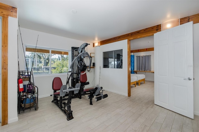 exercise room with light wood-type flooring and baseboards