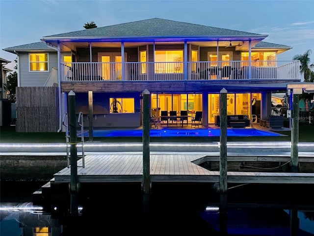 back of property featuring roof with shingles, a patio area, a balcony, and an outdoor pool