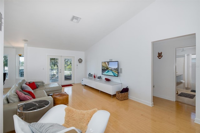 living room with french doors, visible vents, light wood-style floors, high vaulted ceiling, and baseboards