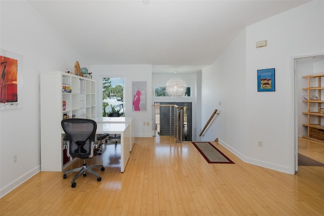 office space featuring light wood-style floors, lofted ceiling, baseboards, and an inviting chandelier