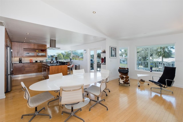 dining room with lofted ceiling, light wood-type flooring, and a healthy amount of sunlight