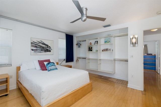 bedroom with visible vents, ceiling fan, baseboards, and hardwood / wood-style flooring