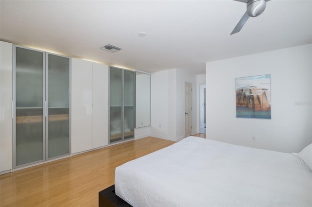 bedroom featuring light wood-style floors, visible vents, and a ceiling fan