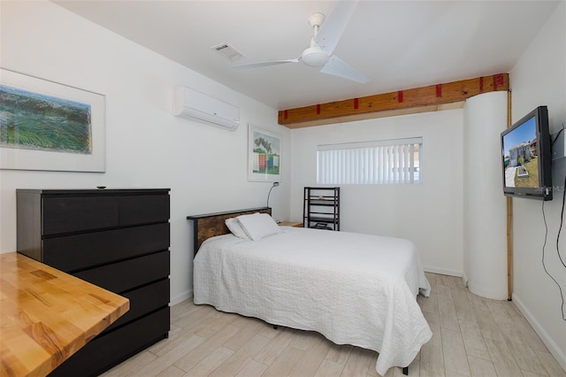 bedroom with beam ceiling, an AC wall unit, visible vents, and light wood finished floors