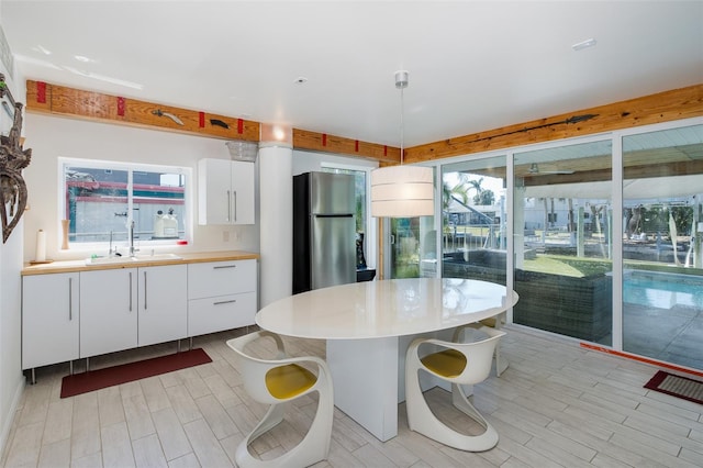 kitchen with a wealth of natural light, a sink, freestanding refrigerator, and white cabinets