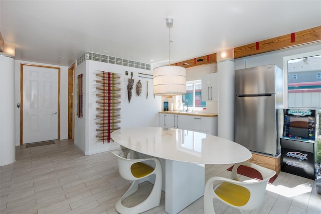 kitchen featuring a breakfast bar, a sink, freestanding refrigerator, and white cabinetry