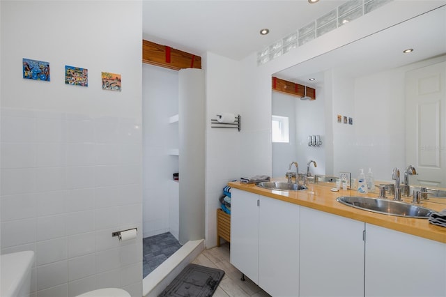 full bathroom with double vanity, a sink, tile walls, and walk in shower