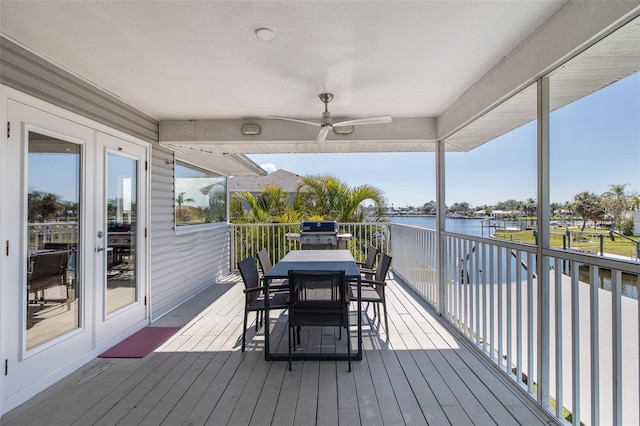 deck featuring ceiling fan, outdoor dining space, grilling area, and a water view