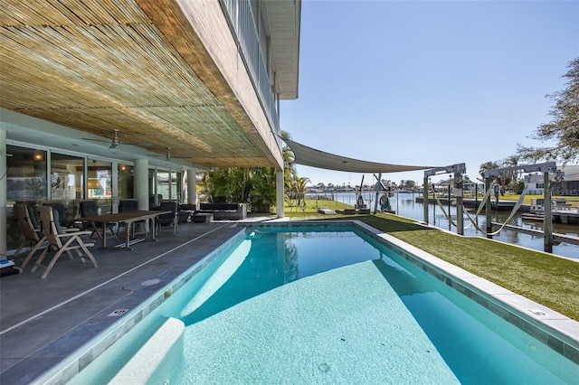 view of pool with a patio, a water view, a lawn, a dock, and a swimming pool