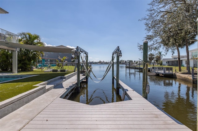 dock area with a water view, boat lift, and a yard