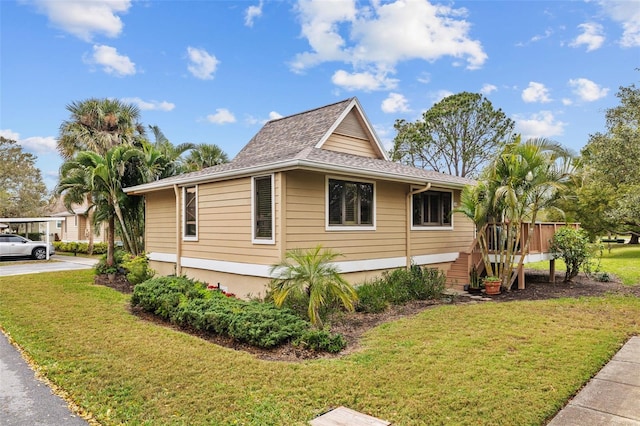 view of side of home with roof with shingles and a lawn