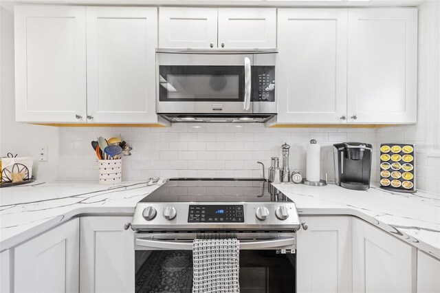 kitchen with light stone counters, white cabinetry, stainless steel appliances, and decorative backsplash