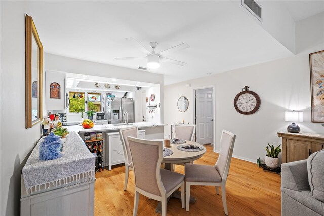 dining area with baseboards, light wood finished floors, visible vents, and a ceiling fan