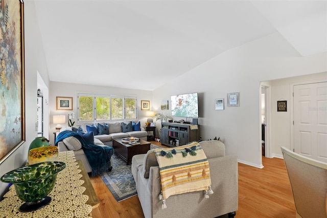 living area featuring light wood-style floors, lofted ceiling, and baseboards