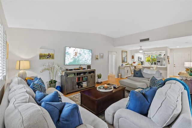 living area featuring visible vents, vaulted ceiling, and wood finished floors