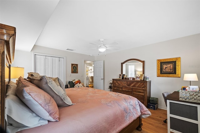 bedroom with a closet, visible vents, a ceiling fan, wood finished floors, and baseboards