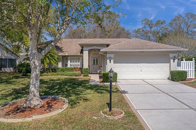 ranch-style home featuring a front lawn, concrete driveway, roof with shingles, stucco siding, and a garage