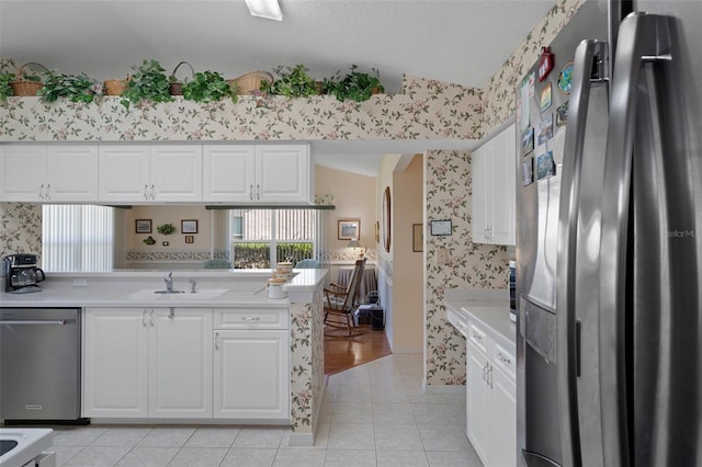 kitchen featuring a sink, stainless steel appliances, and wallpapered walls