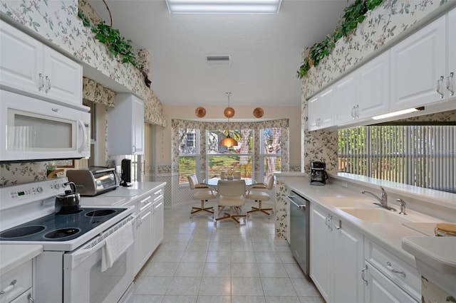 kitchen with wallpapered walls, white appliances, light tile patterned floors, and a sink