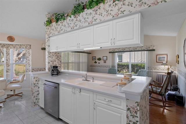 kitchen featuring a sink, wainscoting, wallpapered walls, and stainless steel dishwasher