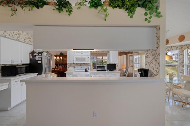 kitchen with light tile patterned floors, white cabinets, stainless steel appliances, and light countertops