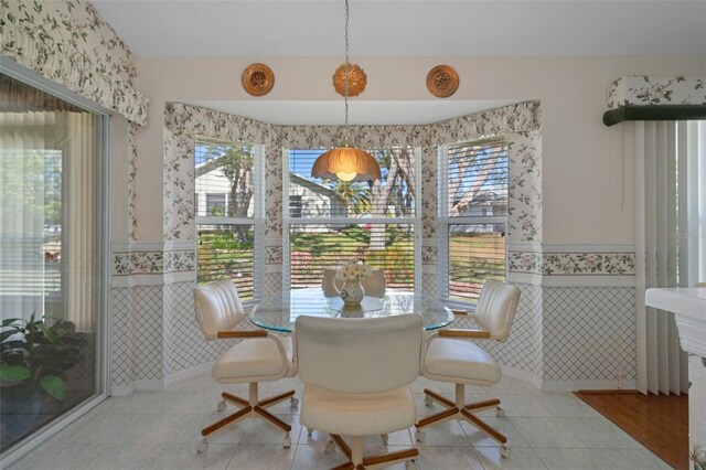 tiled dining room featuring a wainscoted wall and tile walls