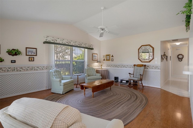 living room featuring ceiling fan, a wainscoted wall, wood finished floors, and vaulted ceiling