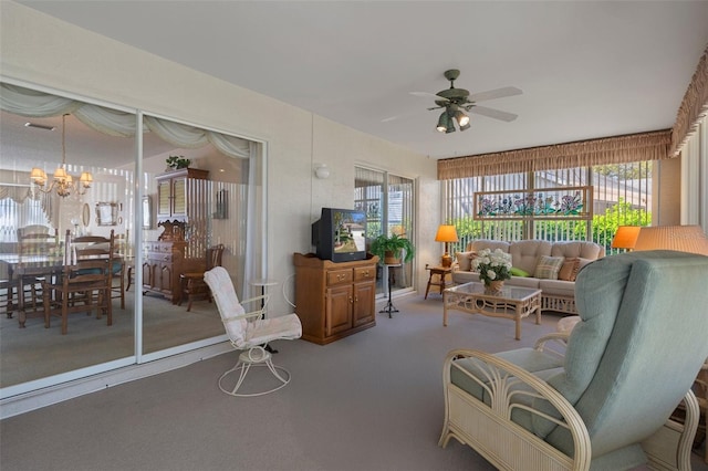 carpeted living room with ceiling fan with notable chandelier