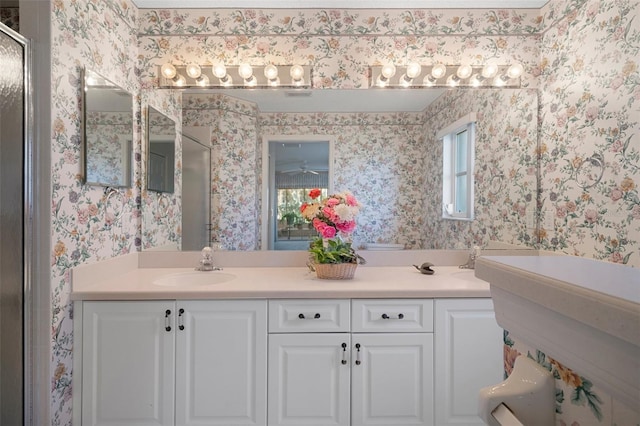 full bath with wallpapered walls, a shower stall, double vanity, and a sink