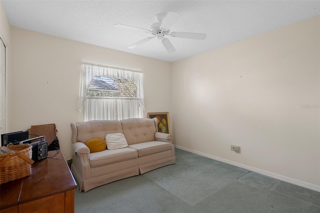 living room with a ceiling fan, baseboards, a textured ceiling, and carpet flooring