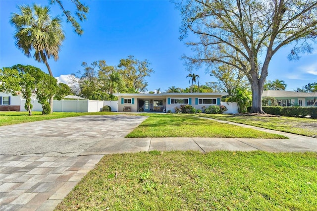 single story home featuring driveway, fence, and a front lawn