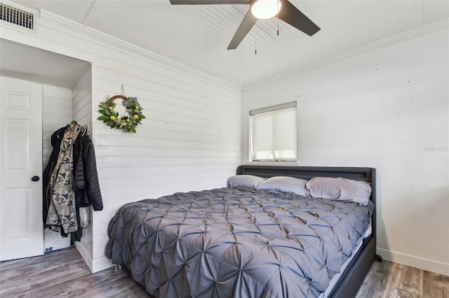 bedroom with baseboards, visible vents, ceiling fan, ornamental molding, and wood finished floors