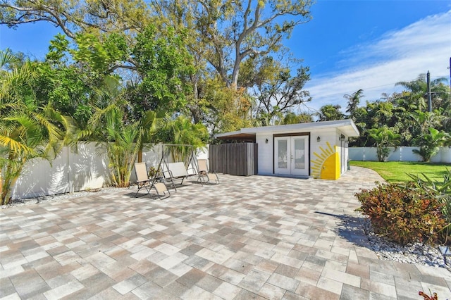 view of patio featuring an outbuilding, french doors, and a fenced backyard