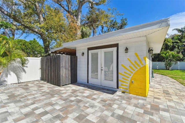 view of outdoor structure featuring a gate, fence, and french doors