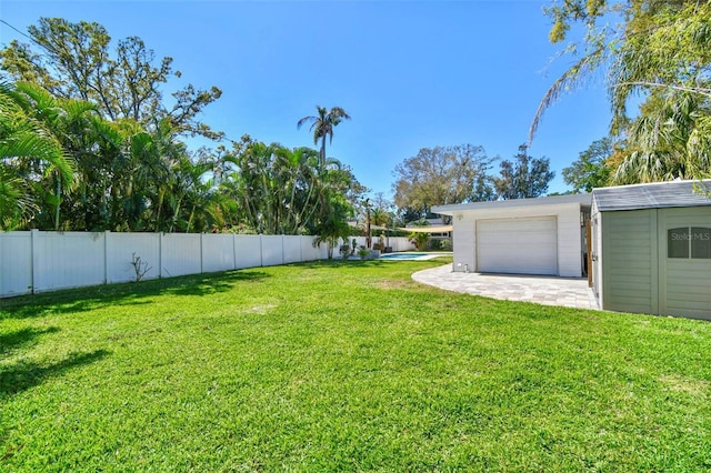 view of yard featuring a garage, fence, and an outdoor structure