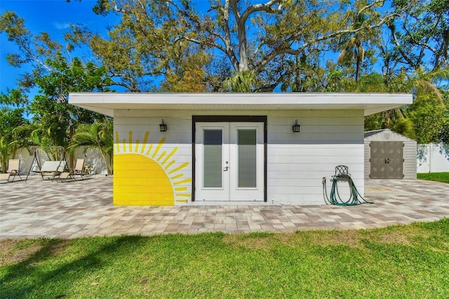 view of outbuilding with french doors, an outdoor structure, and fence