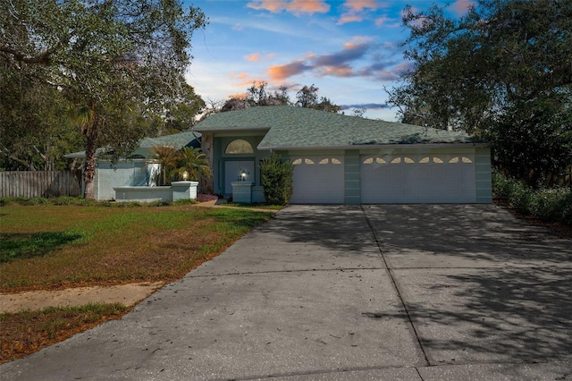 ranch-style house featuring a yard, stucco siding, concrete driveway, fence, and a garage