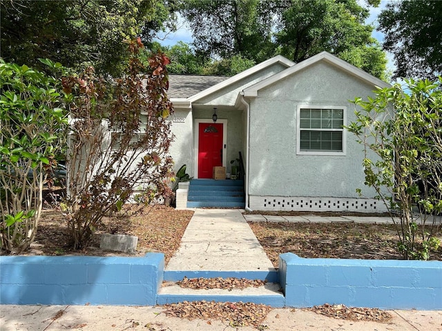 ranch-style home with a shingled roof and stucco siding